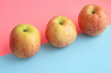 three yellow apples lie horizontally on a pink, blue background. Summer is coming, vitamins, fruits, diet, healthy sweets. Place for text, inscriptions. Beauty, style