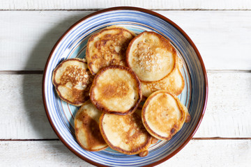 Fritters in blue plate on white wooden background