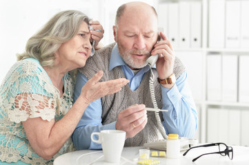 Ill senior couple at home calling doctor