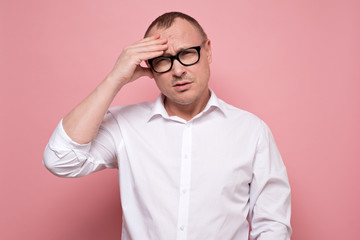 Stressed young man in eyeglasses regretting about something, looking at camera.