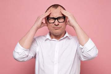 Stressed young man in eyeglasses regretting about something, looking at camera.