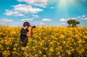 photographer taking pictures of blooming rape field