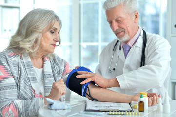 Portrait of elderly doctor measuring blood pressure