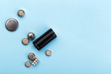 many new and used batteries of different shapes, AA, round batteries on a blue background.