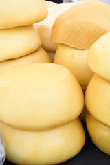 A variety of wheels of cheese seasoned with herbs for sale at the deli counter in the supermarket.