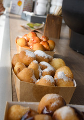 Fresh round small donuts during carnival or fast food festival, glazed with dark and white chocolate
