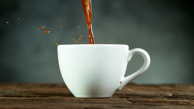 Super slow motion of pouring coffee into cup with copy space. Filmed on high speed cinema camera, 1000fps