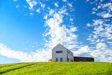 Obraz premium Modern house on green meadow. Blue sky, edit space. Architecture photo.