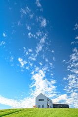 Modern house on green meadow. Blue sky, edit space. Architecture photo.