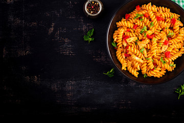Fusilli pasta with chicken and sweet pepper in tomato sauce. Italian Cuisine. Top view, flat lay, overhead