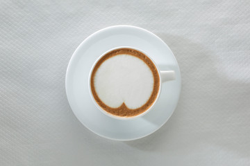 cappuccino in tazza con piattino ripreso dall'alto, isolato su sfondo bianco