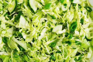 Background vegetarian salad. Spring vegan salad with cabbage, cucumber, green onion and parsley. Top view