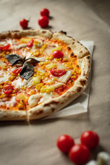 Pizza on the Board top view. Juicy pizza with chicken, pineapple and red tomatoes on a wooden Board and Kraft paper