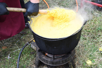 Very large cauldron cooking food during campfire, big pots on fire preparing during food festival.