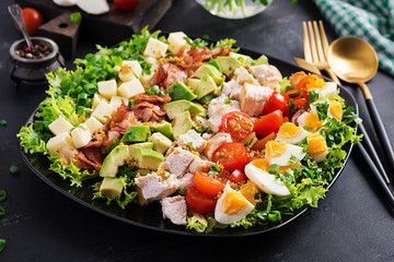 Healthy cobb salad with chicken, avocado, bacon, tomato, cheese and eggs. American food.