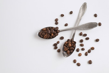 Two teaspoons of coffee and scattered roasted coffee beans. Isolate. Space for text. Top view