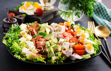 Healthy cobb salad with chicken, avocado, bacon, tomato, cheese and eggs. American food.