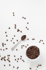 Cup оf coffee , white ceramic cup with roasted coffee beans and a teaspoon on a white background. Isolate. Space for text. Top view