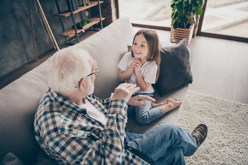 Photo of funny two people old grandpa little interested granddaughter sitting sofa telling good...