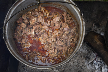 Very large cauldron cooking food during campfire. Cooking in a pot on the fire. Camping concept
