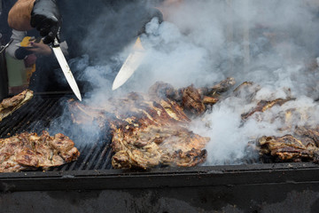 Chef hands cooking a very large piece of meat on the grill. Chef grilling meat on