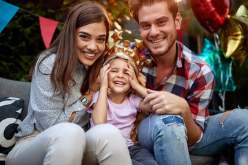 beautiful young coupleposing for a photo with adorable young little girl with a plastic golden crown on her head. togetherness, love concept