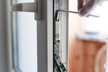 Naklejka premium The man makes the adjustment of the pvc door mechanism with an allen key.