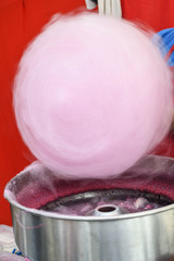 Hand rolling cotton candy in candy floss machine. Making candyfloss during street food festival.