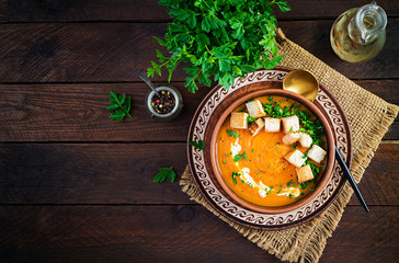 Pumpkin soup in a bowl served with croutons and parsley. Vegan diet soup. Vegetarian food. Top view, overhead