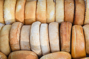 A variety of wheels of cheese seasoned with herbs for sale at the deli counter in the supermarket.