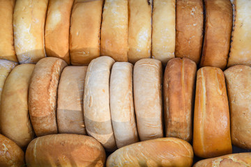 A variety of wheels of cheese seasoned with herbs for sale at the deli counter in the supermarket.