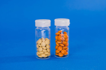 two glass packets of orange and white tablets. one is upside down