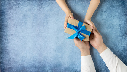 Happy father's day.Gift in the hands of daughter and father on a blue background.I love you,...