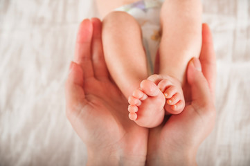 Legs of a newborn in hands closeup. Baby's feet and copy space. Infant care and colic
