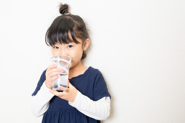 コップで水を飲む笑顔の女の子