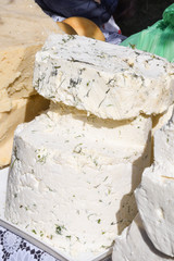 A sliced piece of cheese with dill and spices, for sale on counter top, during food festival.