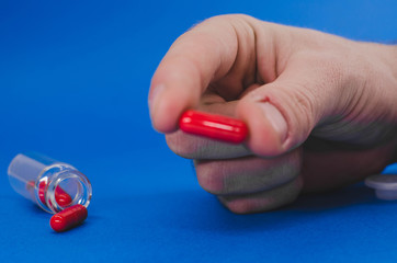 a man's hand is holding a red pill