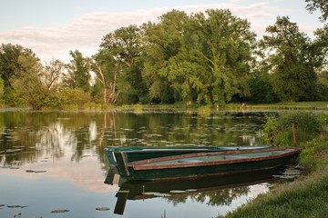 Natural area with several lakes along Sava river in Croatia. Wooden boat and trees reflected in water