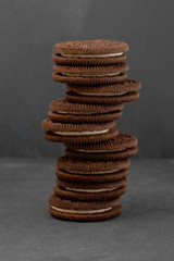 Chocolate cookies with cream filling tower on concrete background.