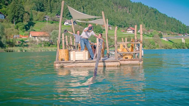 Old and young Caucasian men solute on Hlodovc log-raft floating, Muta, Slovenia