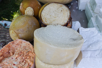 A variety of wheels of cheese seasoned with herbs for sale at the deli counter in the supermarket.