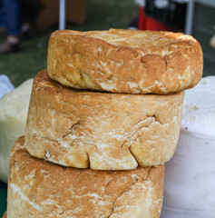 A variety of wheels of cheese seasoned with herbs for sale at the deli counter in the supermarket.