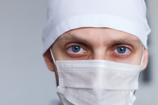 Tired Young Man Doctor In Mask During Coronavirus. Dramatic Portrait Of Medic, Close-up