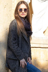 Fashionable girl posing on a wooden background.building with yellow brick. Spring weather, sunny day. Warm day.