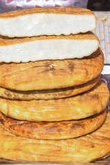 A variety of wheels of cheese seasoned with herbs for sale at the deli counter in the supermarket.