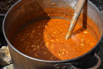 Very large cauldron cooking food during campfire. Cooking in a pot on the fire. Camping concept