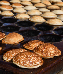 Typical Dutch poffertjes - tiny pancakes-being baked on a heavy cast iron pan