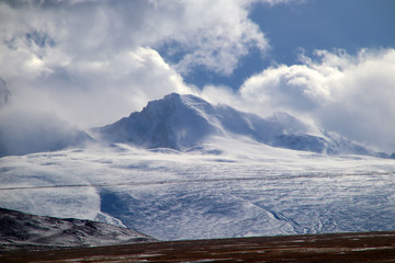 Plateau, Hochspannungsmast, blauer Himmel und weiße Wolken, Eissee und ferner Shishapangma-Gipfel
