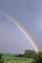 Regenbogen und alter Turm mit dunklen Regenwolken in ländlicher Landschaft