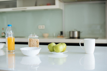 corn flakes, apples, milk, orange juice and cup of coffee for breakfast in kitchen